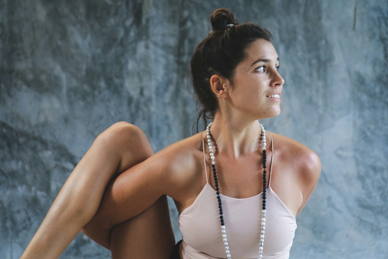 Woman in white tank top and white beaded necklace in soft daylight